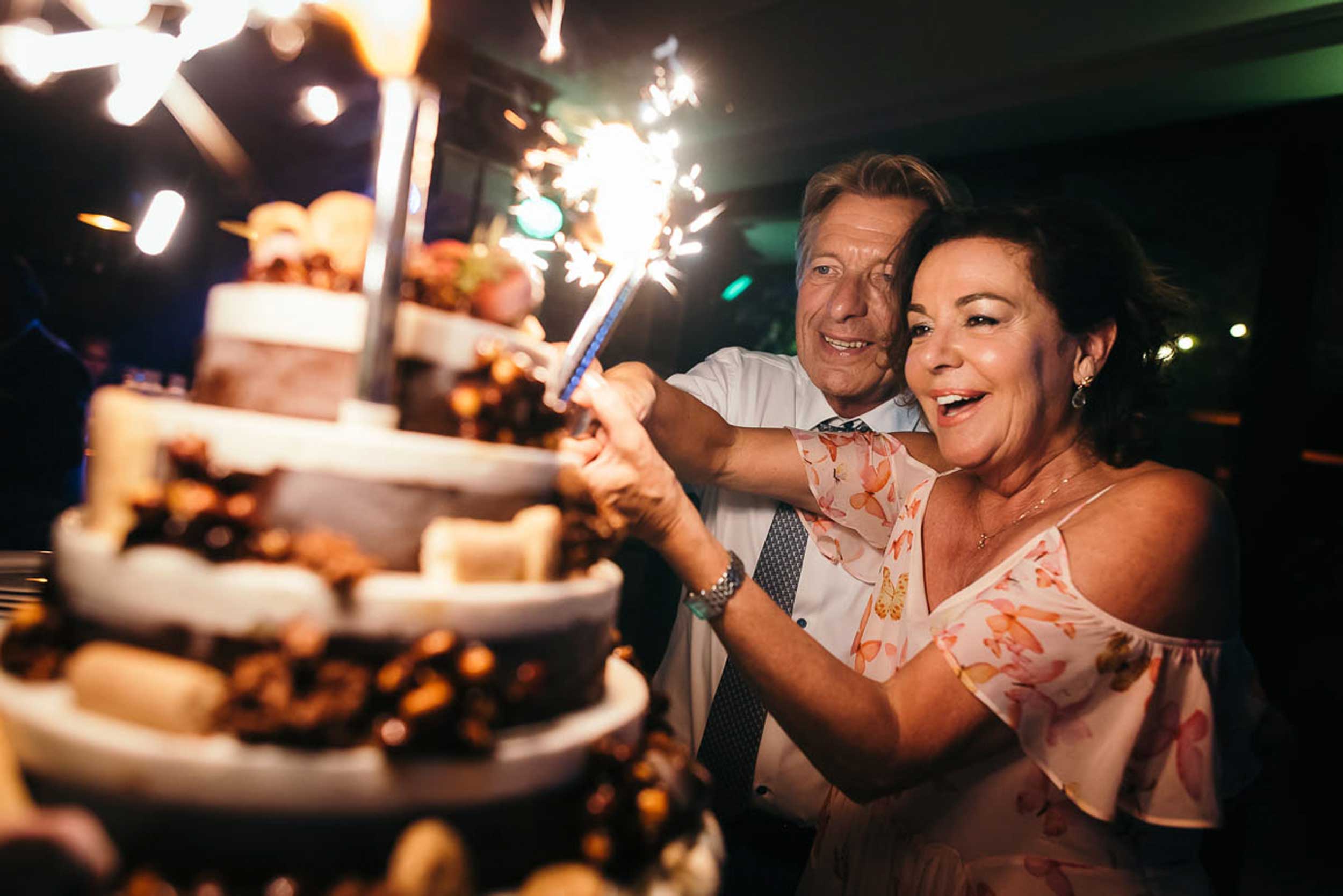 Ervaren liefde: Bruidspaar op leeftijd snijdt de taart aan, met een guitige blik tussen de bruid en bruidegom.